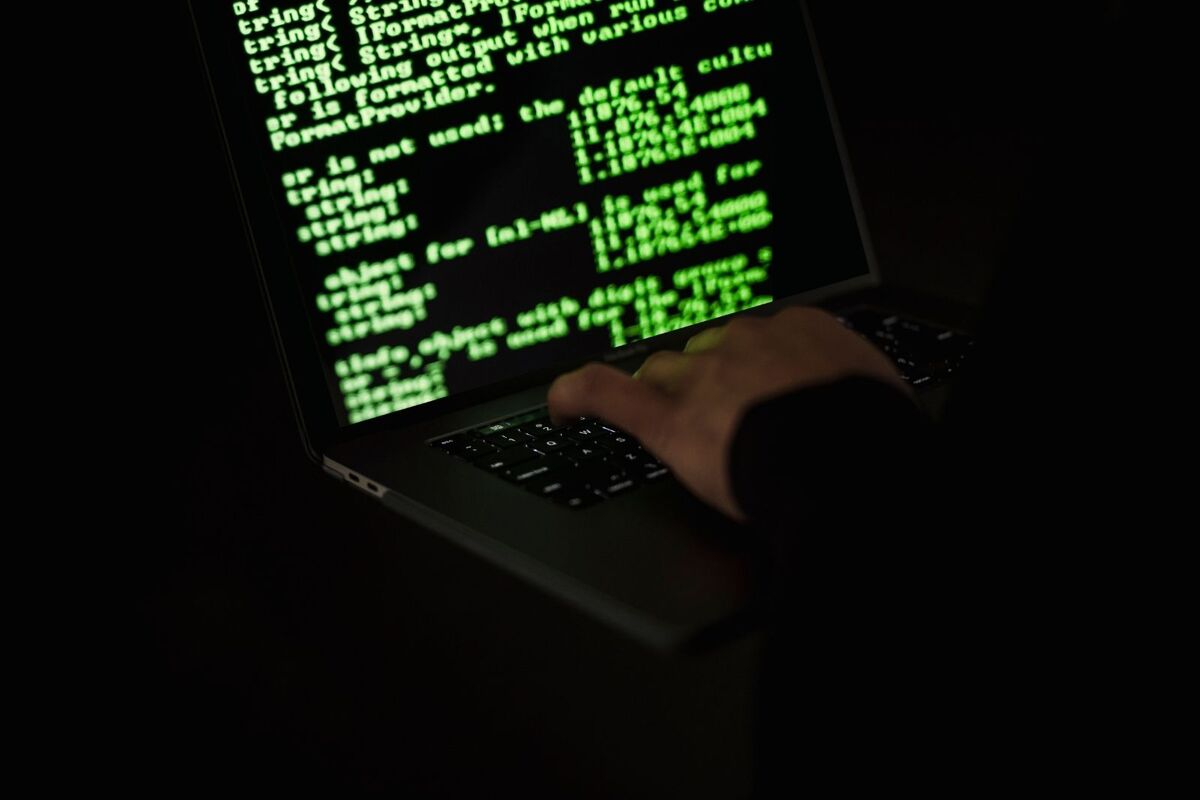 Foto de unas manos manipulando un ordenador portátil para lanzar un ciberataque